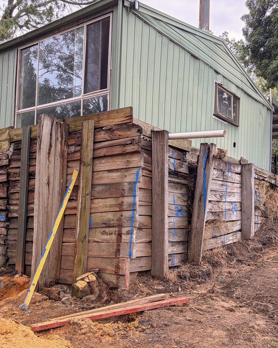 Failed timber retaining wall leaning away from the bank it was holding