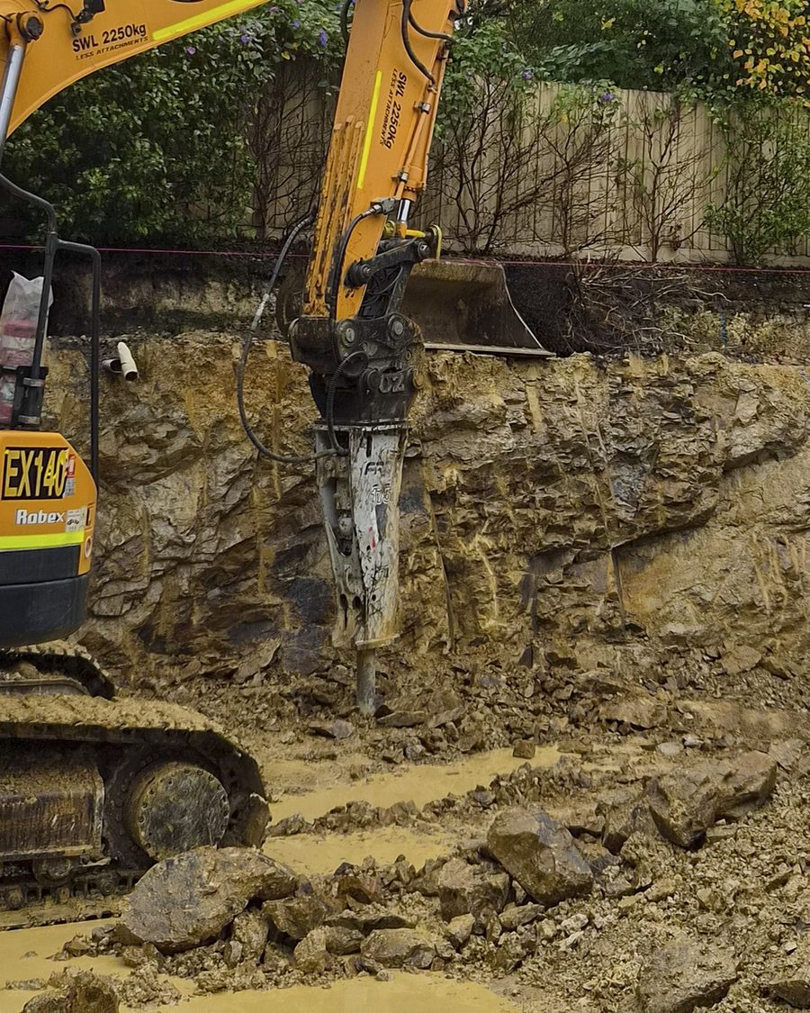 Excavator with a hydraulic hammer breaking rock