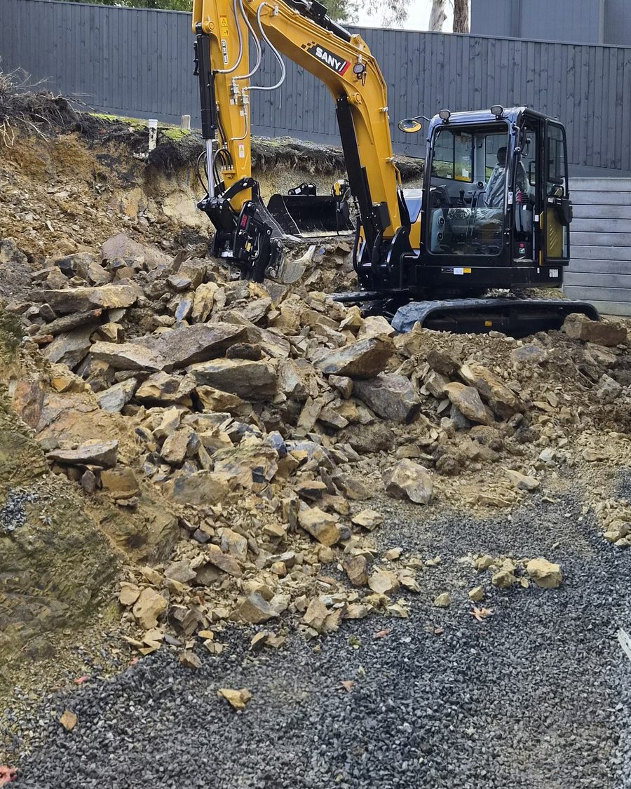 Excavator cutting a bench into a steep rock face