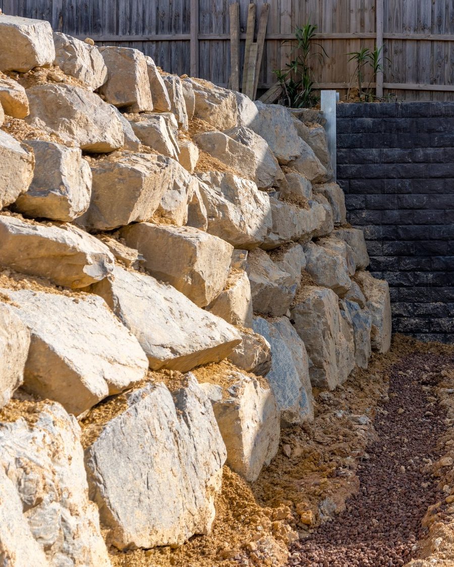 Large quarry boulders placed by machine against an engineered wall
