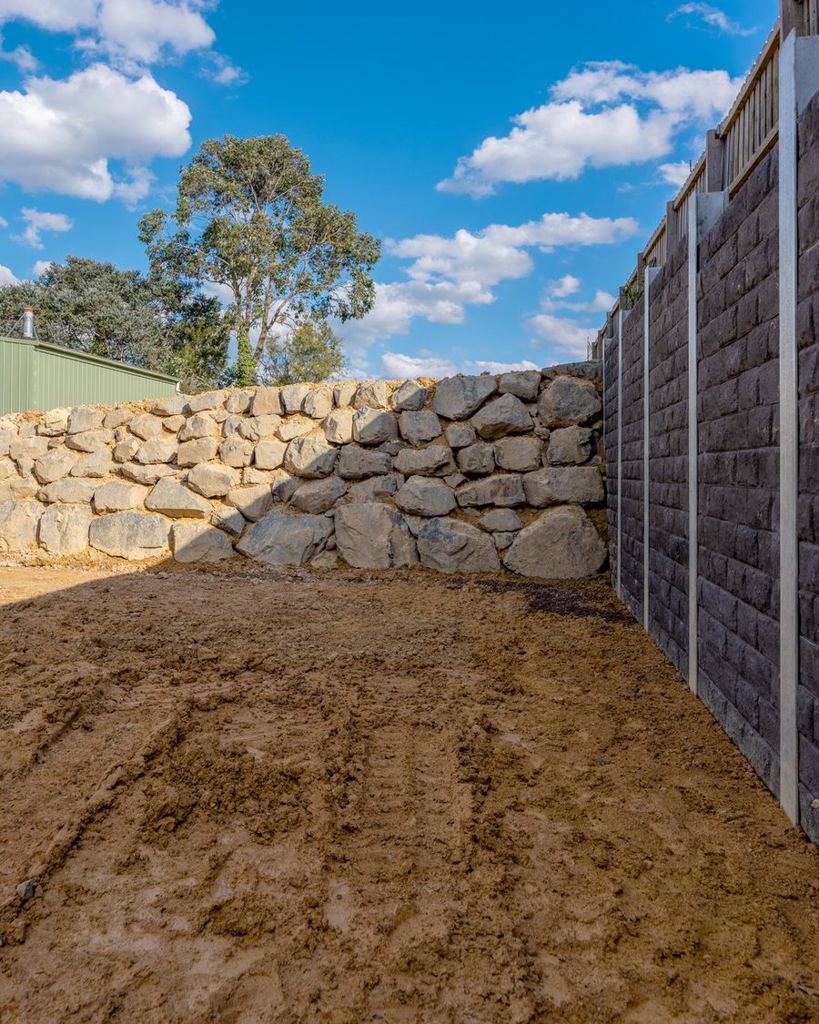 Transition between a quarry rock wall and a concrete sleeper retaining wall