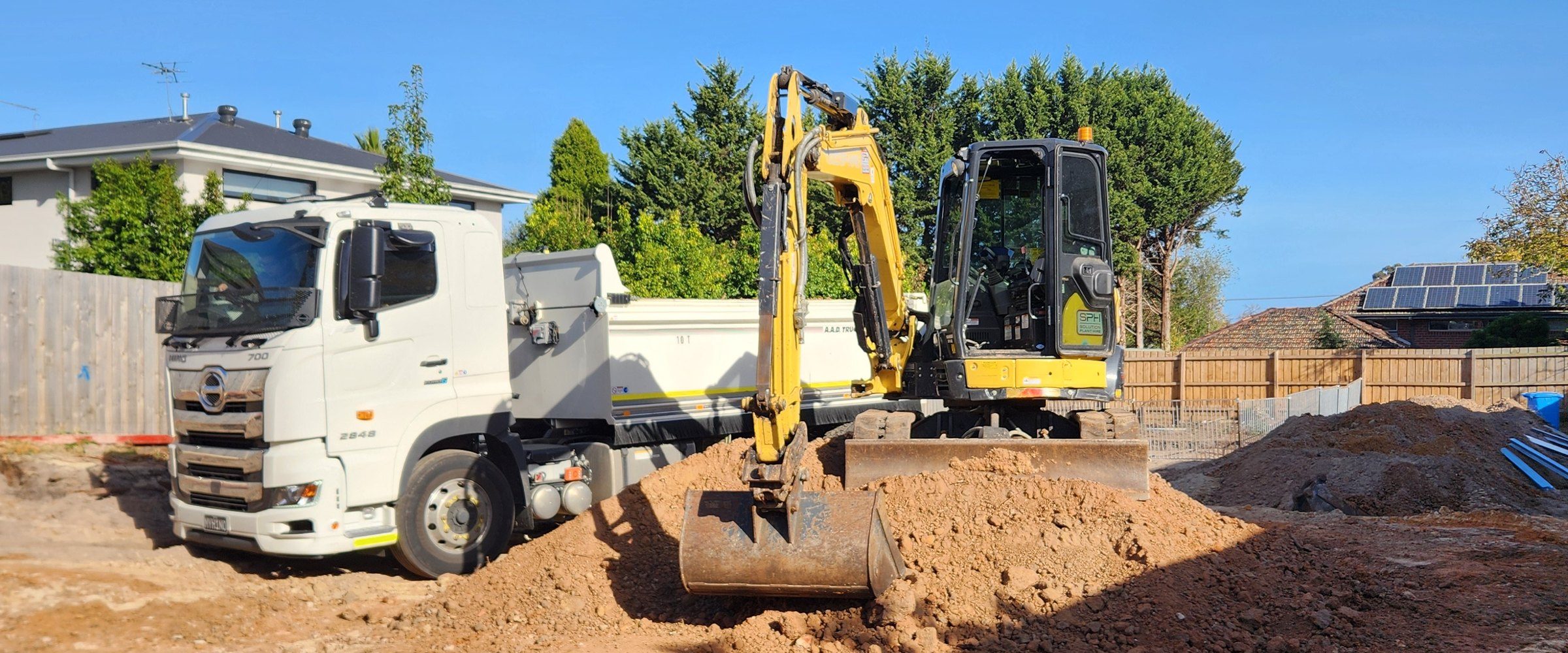 Excavator loading spoil into a tipper truck on a rock site, both owned and operated by Eastern Melbourne Earthworks